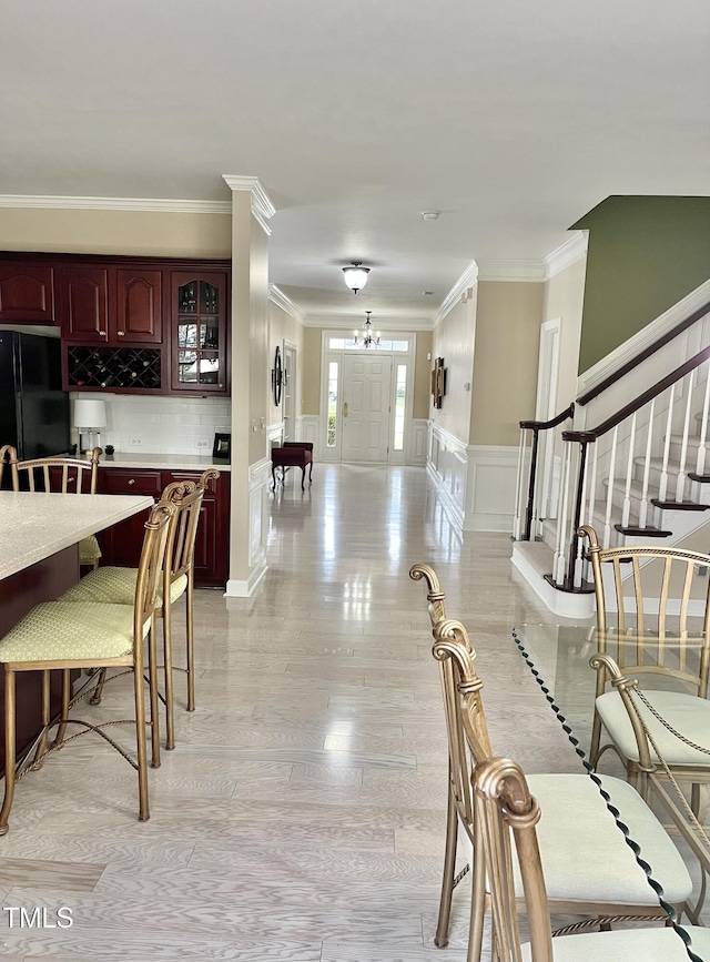 living room featuring ornamental molding, stairs, a decorative wall, and a wainscoted wall
