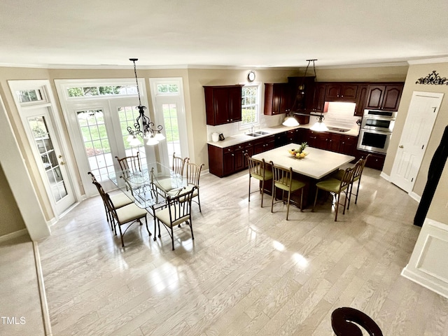 dining area featuring crown molding, light wood-style flooring, and baseboards