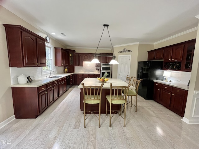 kitchen with freestanding refrigerator, a sink, a breakfast bar area, double oven, and backsplash