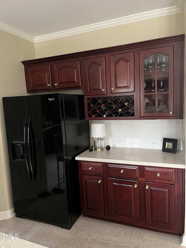 bar area with black fridge, decorative backsplash, and ornamental molding