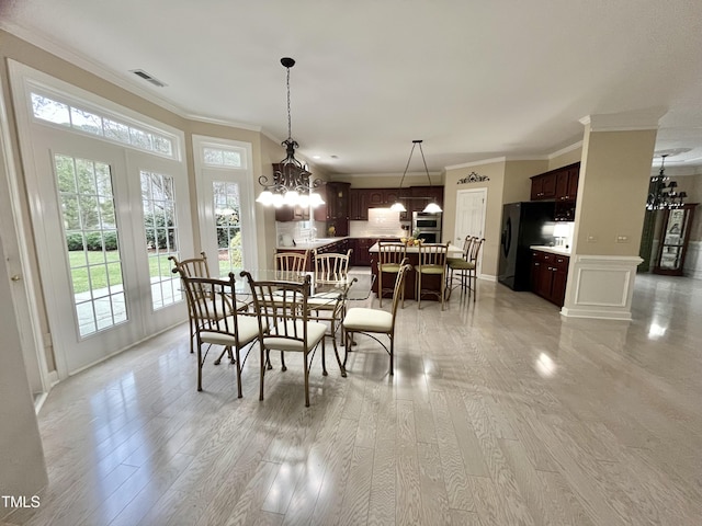 dining area featuring crown molding, light wood-style floors, a chandelier, and baseboards