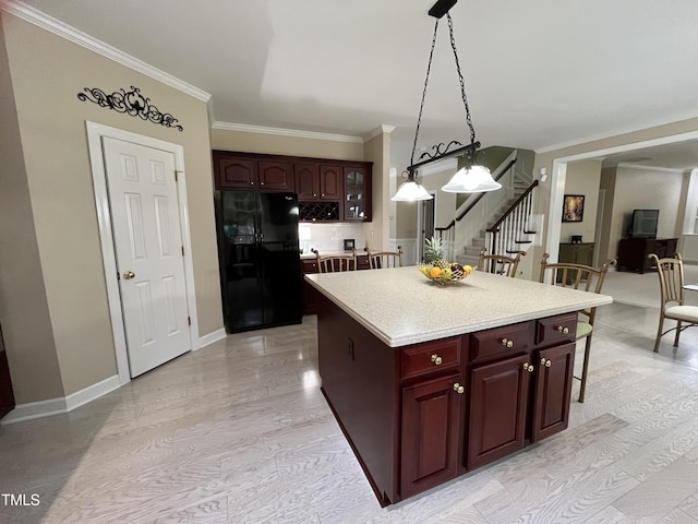kitchen featuring black fridge, crown molding, decorative light fixtures, light countertops, and a center island