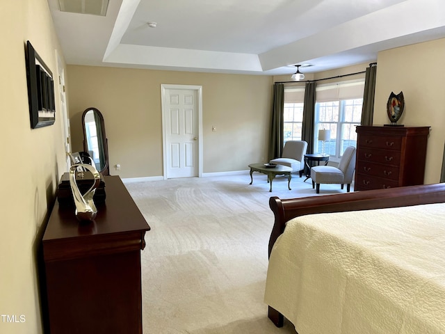 carpeted bedroom featuring a raised ceiling and baseboards