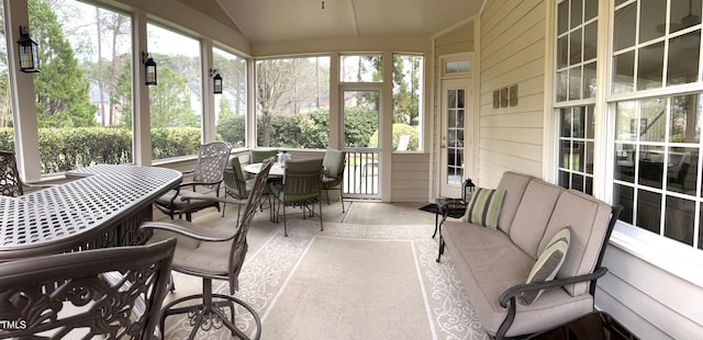 sunroom / solarium with lofted ceiling and outdoor dining area