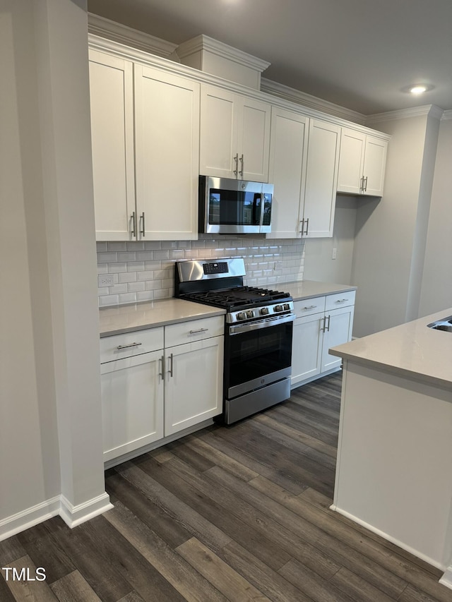 kitchen featuring stainless steel appliances, white cabinets, light countertops, dark wood-type flooring, and ornamental molding