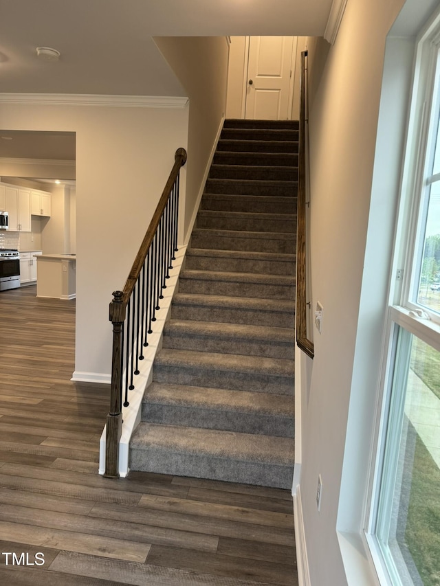 staircase featuring wood finished floors, crown molding, and baseboards