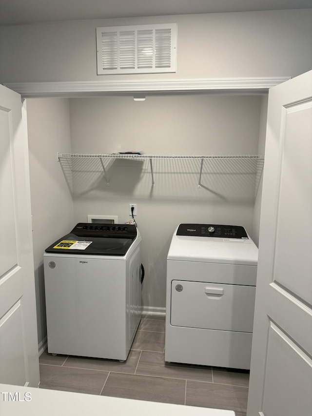 laundry area featuring washer and dryer, baseboards, and light tile patterned floors