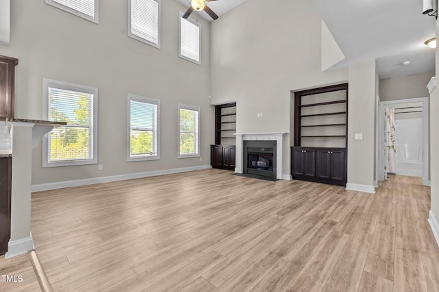 870 Kentucky Derby Ln, Lillington, NC 27546 - unfurnished living room with a ceiling fan, light wood-style flooring, healthy amount of natural light, a fireplace with flush hearth, and a high ceiling