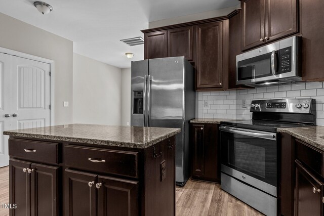870 Kentucky Derby Ln, Lillington, NC 27546 - kitchen with stainless steel appliances, light wood-style floors, decorative backsplash, a kitchen island, and dark brown cabinetry