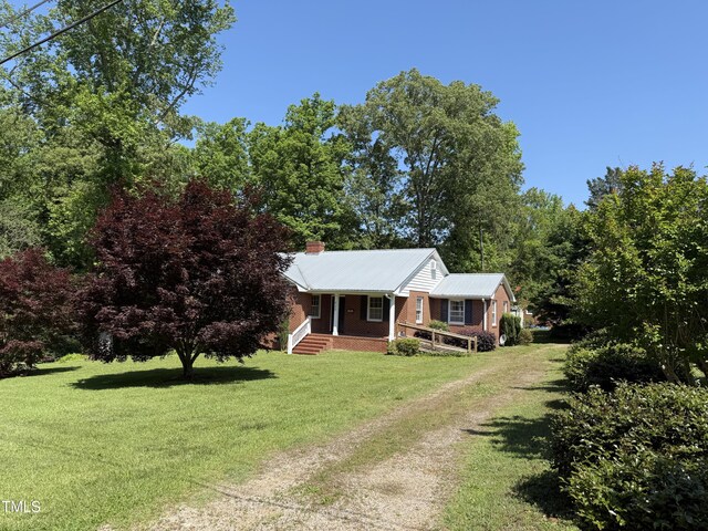 420 Rodwell St, Warrenton, NC 27589 - view of front of house featuring covered porch, driveway, a front lawn, a chimney, and metal roof