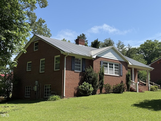 420 Rodwell St, Warrenton, NC 27589 - view of side of home with a lawn, brick siding, a chimney, and metal roof