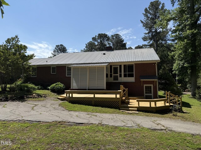 420 Rodwell St, Warrenton, NC 27589 - rear view of house featuring a deck, brick siding, metal roof, and a lawn