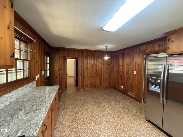 420 Rodwell St, Warrenton, NC 27589 - kitchen featuring stainless steel fridge, wood walls, brown cabinets, light flooring, and baseboards