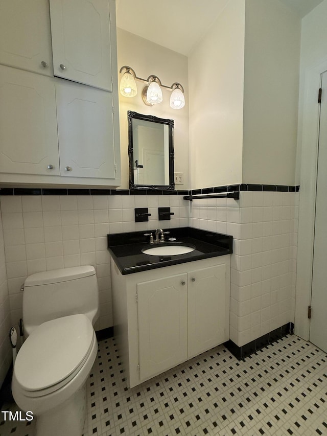 420 Rodwell St, Warrenton, NC 27589 - bathroom with tile walls, toilet, vanity, a wainscoted wall, and tile patterned flooring