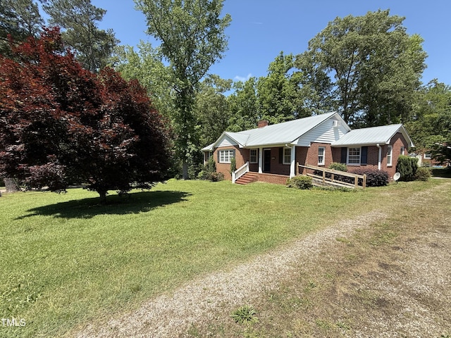 420 Rodwell St, Warrenton, NC 27589 - view of front facade with brick siding, a chimney, a front yard, covered porch, and metal roof