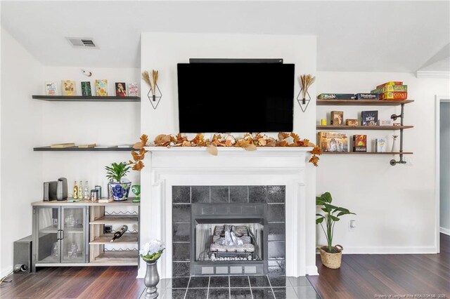 living area with a tile fireplace, wood finished floors, and baseboards