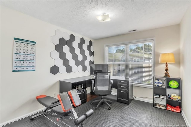office with baseboards, dark carpet, and a textured ceiling
