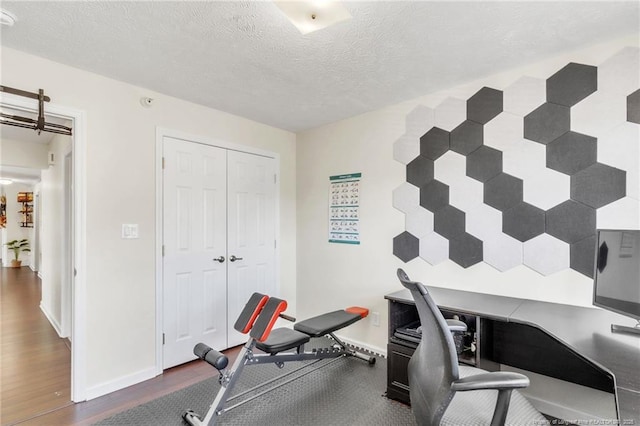 office space featuring wood finished floors, baseboards, and a textured ceiling