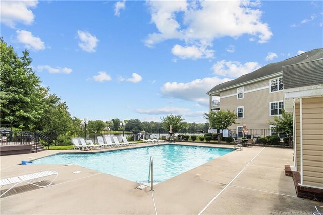 community pool with a patio and fence