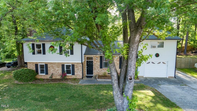 split level home featuring concrete driveway, an attached garage, and brick siding