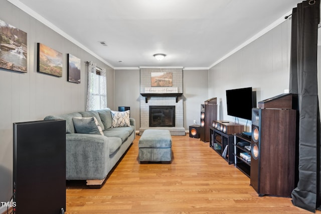 living room featuring ornamental molding, light wood finished floors, and a brick fireplace