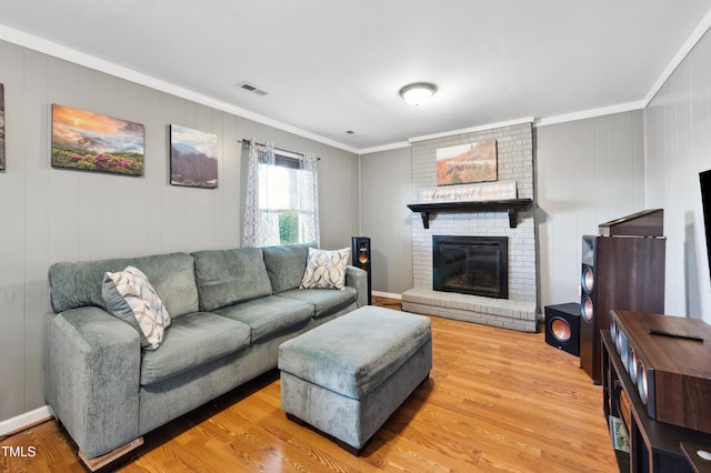 living room featuring ornamental molding, light wood-type flooring, and a fireplace