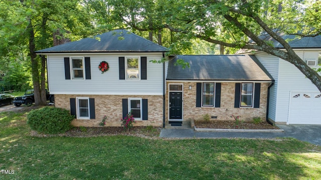 split level home with an attached garage, a front lawn, and brick siding