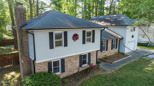 view of front of home with a chimney, fence, brick siding, and an attached garage