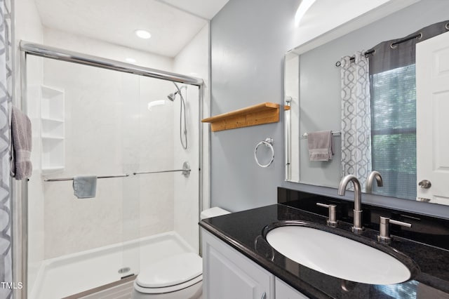 full bathroom featuring a stall shower, toilet, and vanity