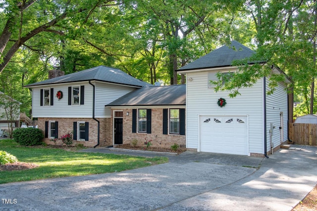 split level home with a chimney, a garage, concrete driveway, roof with shingles, and brick siding