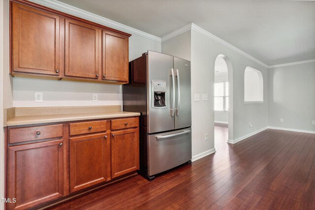 kitchen with stainless steel fridge, light countertops, crown molding, baseboards, and dark wood-style floors