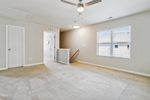 unfurnished room with attic access, baseboards, ceiling fan, and light carpet