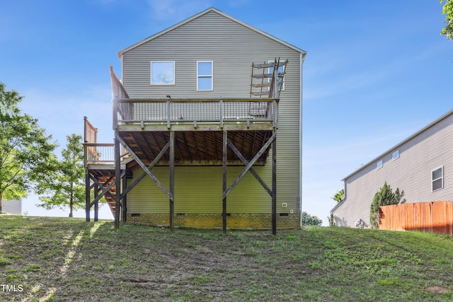 rear view of property with a wooden deck, crawl space, and fence