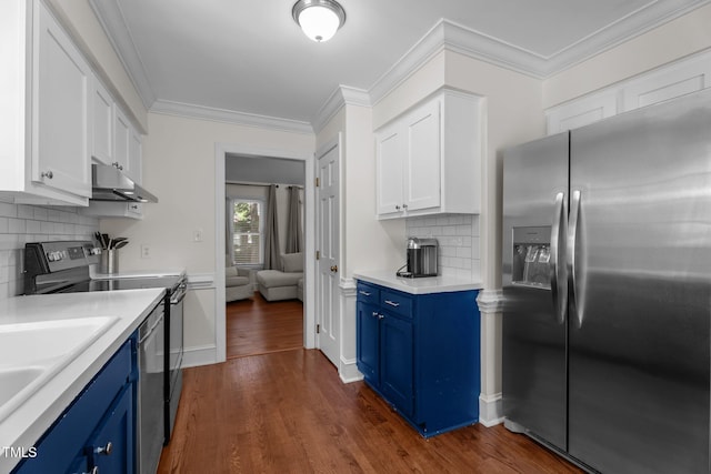 kitchen with appliances with stainless steel finishes, blue cabinets, under cabinet range hood, white cabinets, and crown molding
