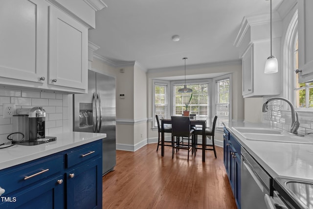 kitchen with blue cabinets, stainless steel appliances, a sink, wood finished floors, and light countertops