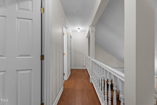 hall with wood finished floors, baseboards, and an upstairs landing