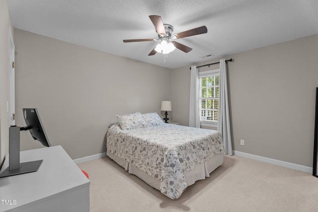 bedroom featuring light colored carpet, baseboards, a textured ceiling, and ceiling fan