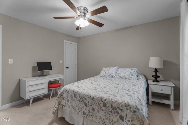 bedroom with light colored carpet, a desk, baseboards, and a ceiling fan