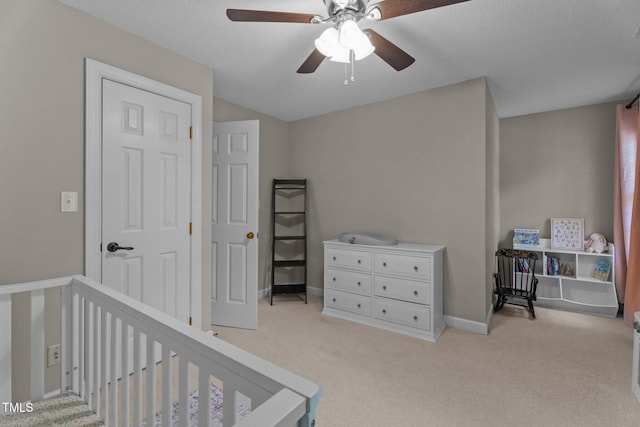 bedroom featuring light carpet, a crib, and a ceiling fan