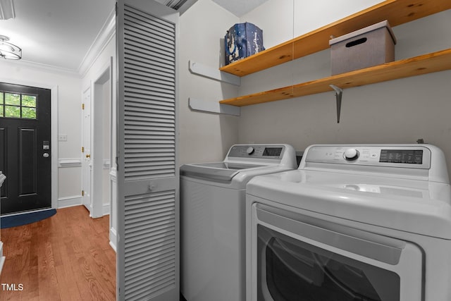 laundry area with light wood finished floors, washer and dryer, crown molding, and baseboards
