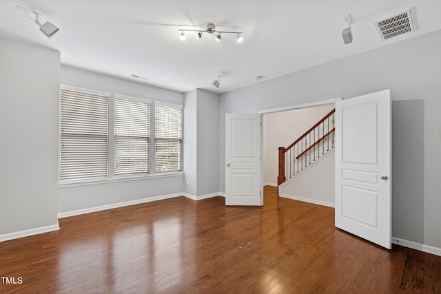 unfurnished living room with stairway, wood finished floors, and baseboards