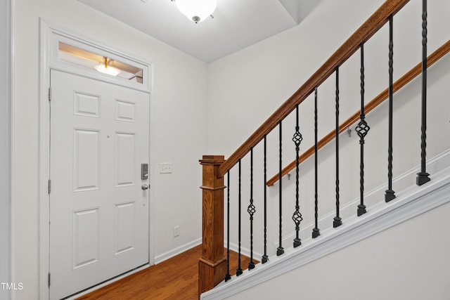 entryway featuring wood finished floors, stairway, and baseboards
