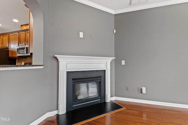 detailed view of stainless steel microwave, refrigerator, baseboards, wood finished floors, and recessed lighting