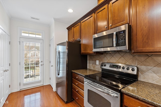 kitchen featuring stainless steel appliances, crown molding, light wood-type flooring, backsplash, and brown cabinetry