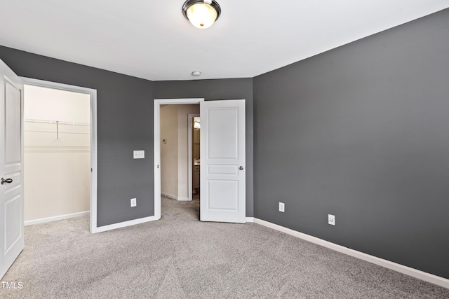 unfurnished bedroom with carpet flooring, baseboards, a walk in closet, and a closet