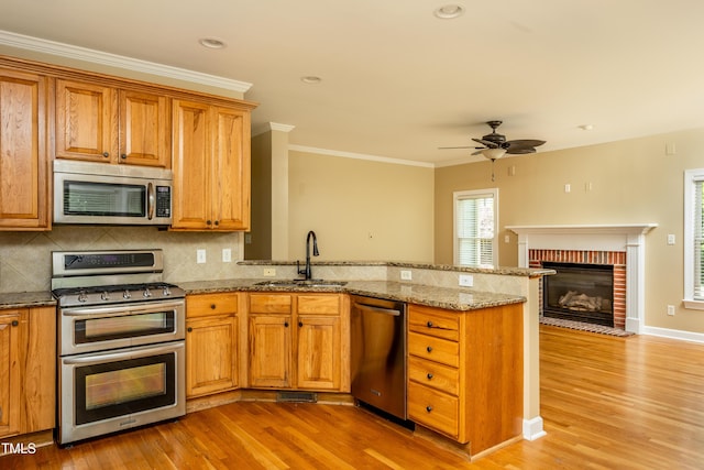 2617 Charenson Pl, Raleigh, NC 27614 - kitchen with appliances with stainless steel finishes, a sink, a ceiling fan, light wood-type flooring, and a peninsula