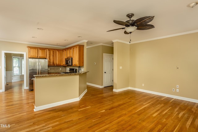 2617 Charenson Pl, Raleigh, NC 27614 - kitchen featuring appliances with stainless steel finishes, light wood-type flooring, a ceiling fan, brown cabinetry, and stone countertops