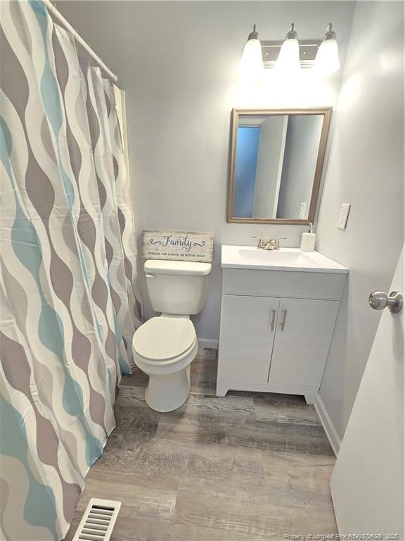 6841 Radial Dr, Fayetteville, NC 28311 - full bathroom with wood finished floors, vanity, toilet, and baseboards