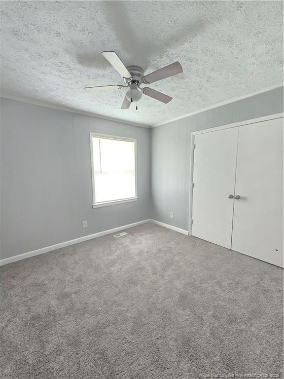 6841 Radial Dr, Fayetteville, NC 28311 - unfurnished bedroom with a textured ceiling, ceiling fan, a closet, crown molding, and carpet flooring