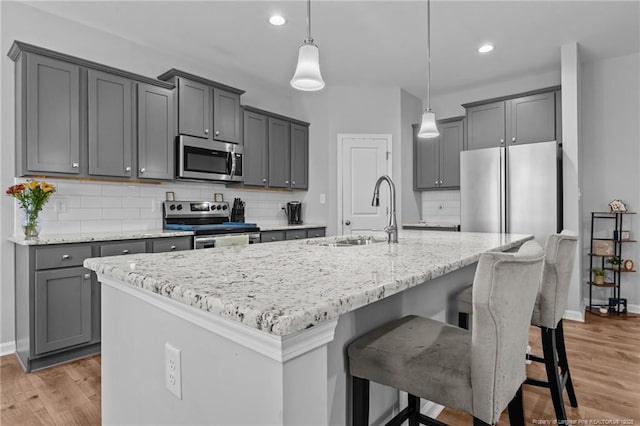 308 Laurel Lake Rd, Salemburg, NC 28385 - kitchen with appliances with stainless steel finishes, a sink, light stone counters, baseboards, and light wood-style floors